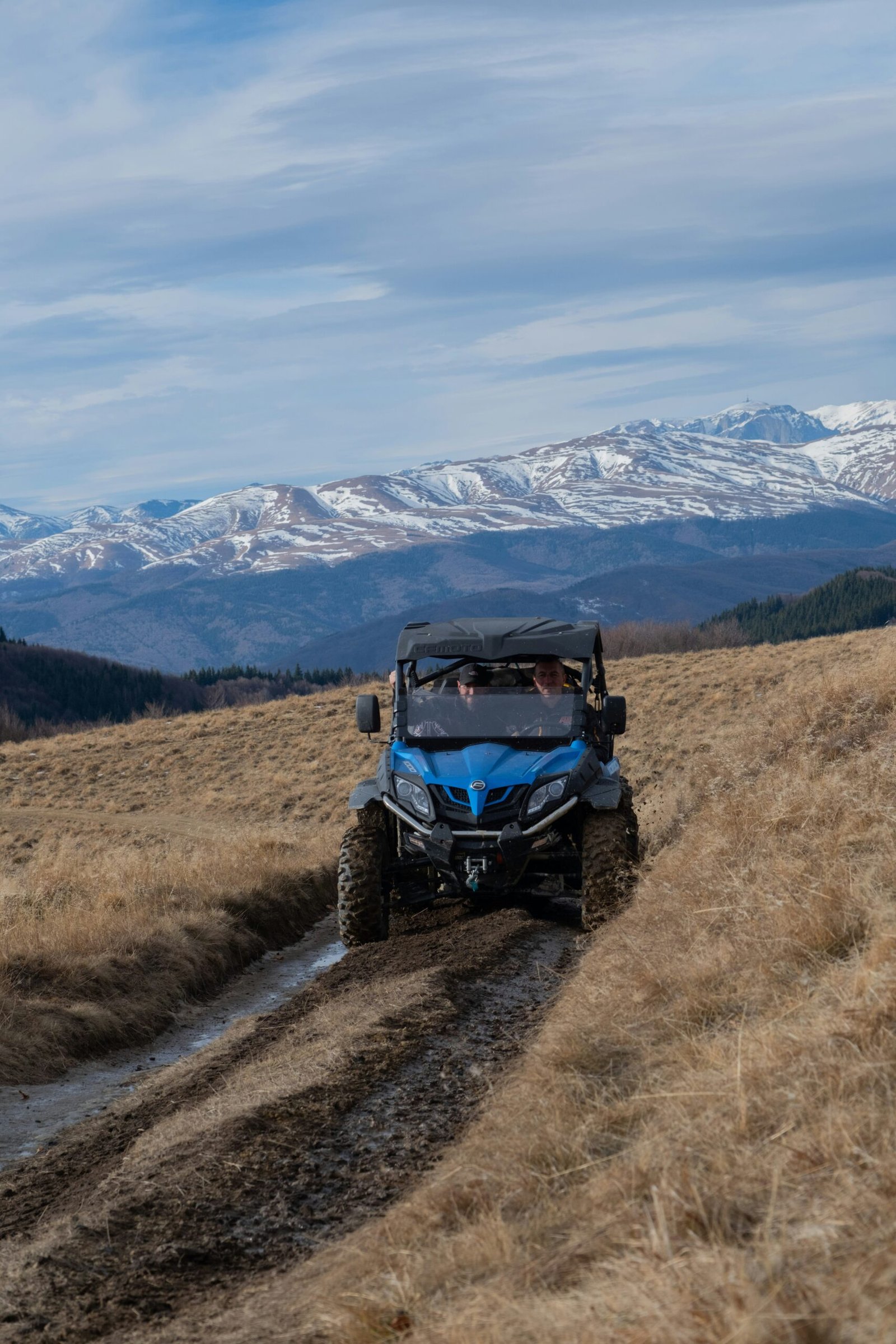 a blue four - wheeler utvs driving down a dirt road